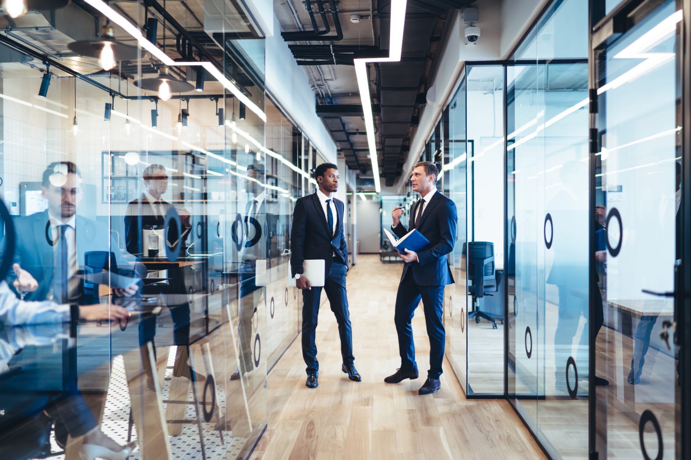 Deux hommes en costume ont une conversation dans un couloir de bureau